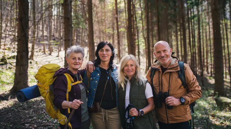 Vier Wanderer im mittleren Alter machen ein Gruppenfoto im Wald
