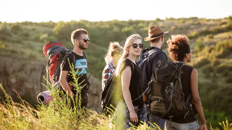 5 Freunde Wandern bei Sonnenuntergang im hohen Gras