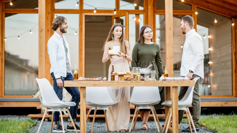 Vier junge Freunde stehen bei gedecktem Tisch im Freien und unterhalten sich