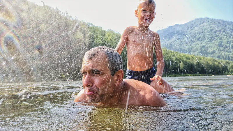 Älterer Mann wird von lachendem Kind mit Wasser abgespritzt