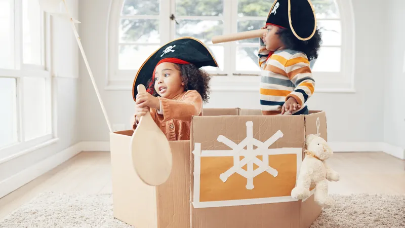 Zwei Kinder mit Piratenmütze spielen in einem verzierten Karton Piraten