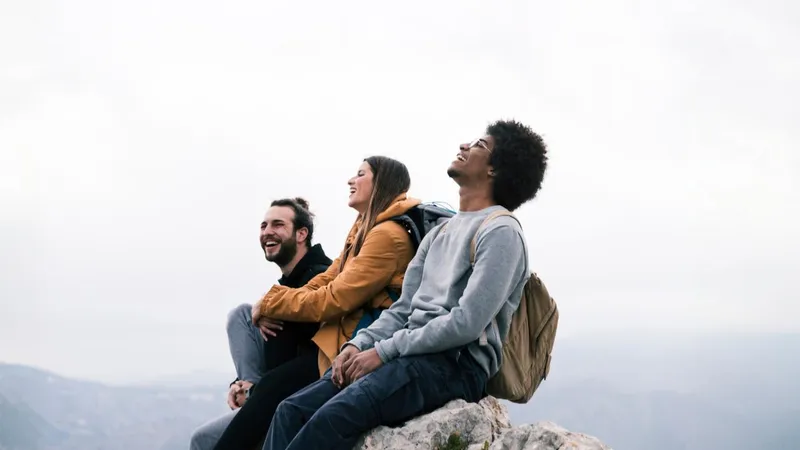 Drei Freunde sitzen lachend am nebligen Berggipfel