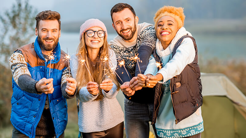 Vier Freunde im freien feiern mit Sprühkerzen