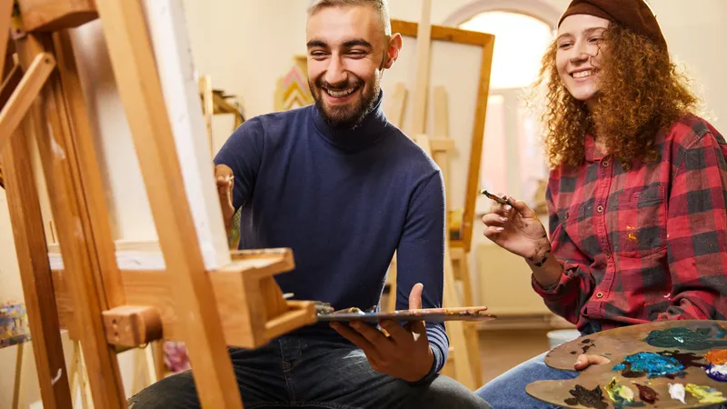 Junger Mann und junge Frau sitzen gemeinsam vor einer Leinwand