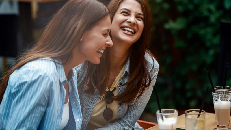 Zwei Freundinnen lachen herzlich beim Kaffee trinken