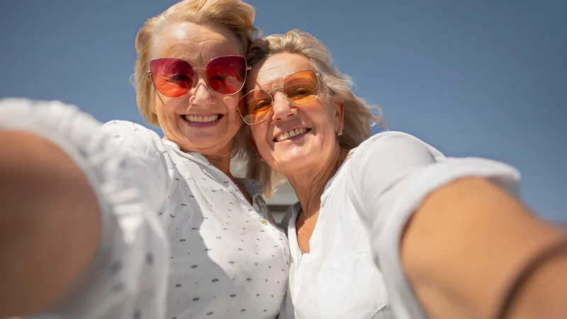 Zwei ältere Freundinnen mit bunten Sonnenbrillen machen ein Selfie