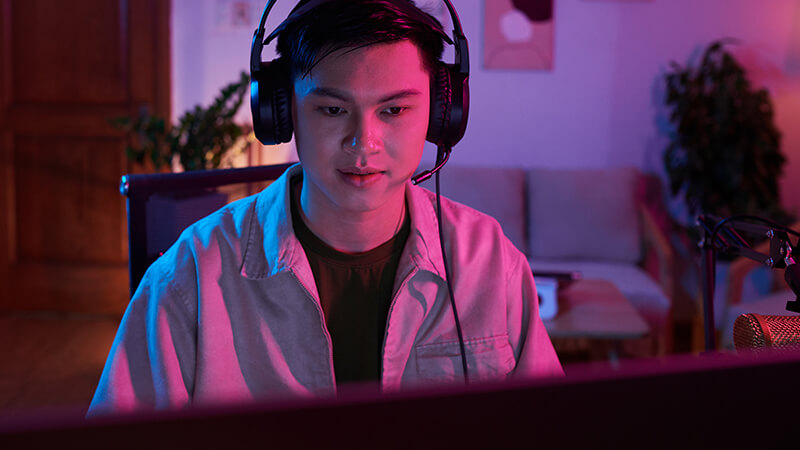 Junger Mann blickt in einen Bildschirm mit einem Headset am Kopf