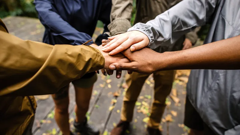 Fünf Freunde stehen im Kreis und legen ihre Hände übereinander