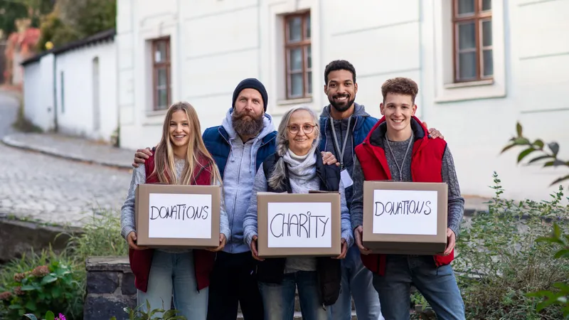 Fünf freiwillige Helfer lachen in die Kamera und halten drei Spendenboxen im Arm.