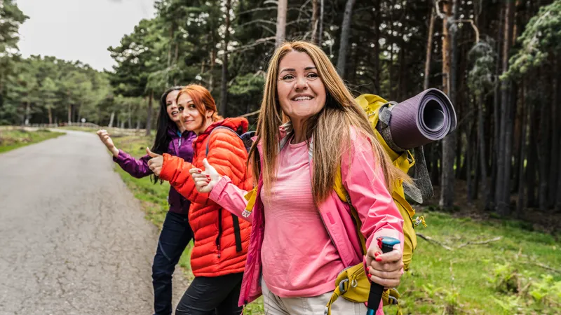  Freundinnen stehen mit Wanderrucksack am Straßenrand