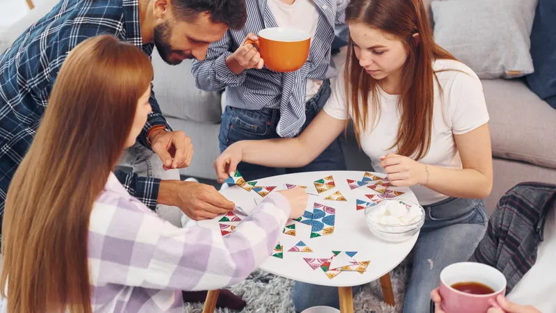 Freunde spielen ein Brettspiel am Couchtisch und trinken dabei Tee