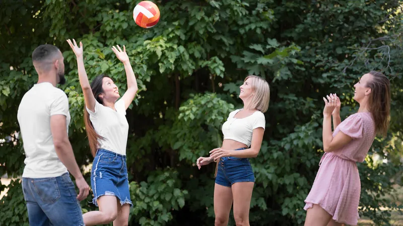 Vier Freunde spielen Volleyball im Park