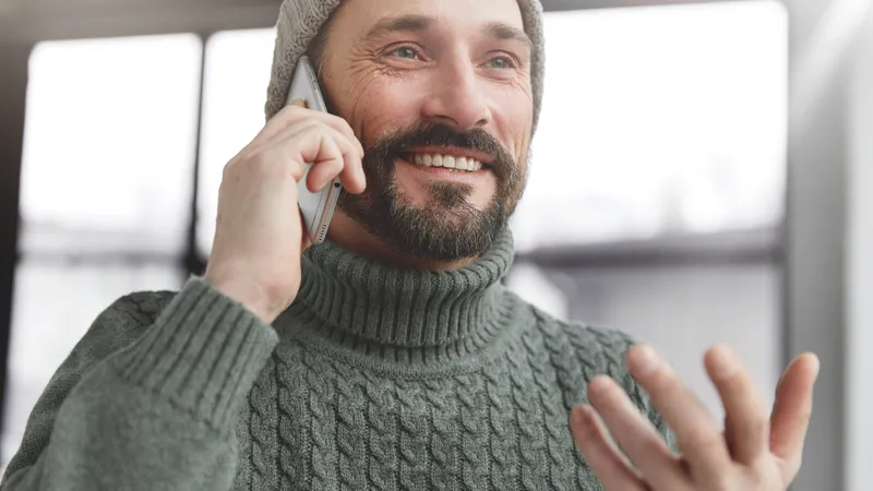 Lächelnder Mann mit Haube telefoniert mit seinem Handy