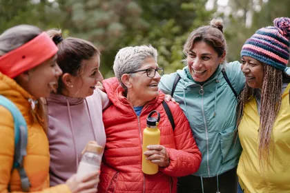 Lachende fünf Freundinnen, Schulter an Schulter, beim Wandern