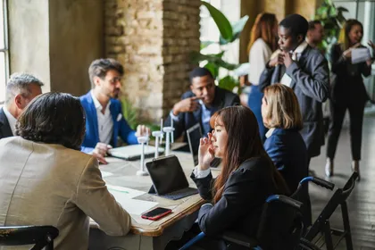 Menschen in Business-Kleidung unterhalten sich am Tisch.