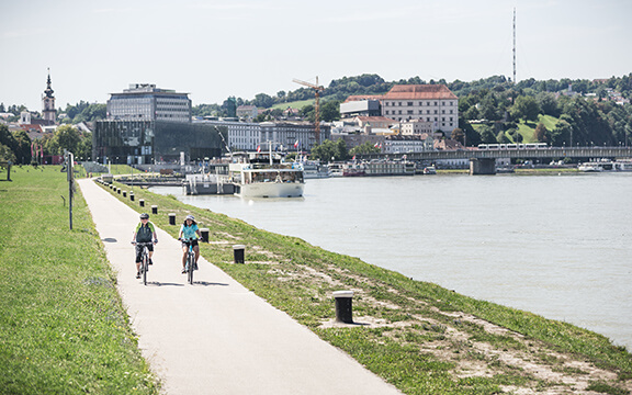 Zwei Radfahrer fahren am Donauradweg in Linz
