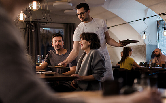 Freunde unterhalten sich im Restaurant und bekommen essen serviert