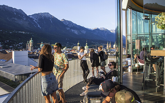 Junge Leute genießen den Sonnenuntergang auf einer Dachterrasse in Innsbruck