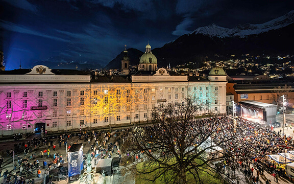 Panorama-Bild vom Innsbrucker Bergsilvester mit beleuchteten Häuserfronten und feiernden Menschen