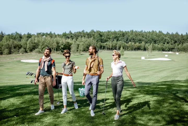 Vier Freunde unterhalten sich am Golfplatz am Weg zum nächsten Abschlag