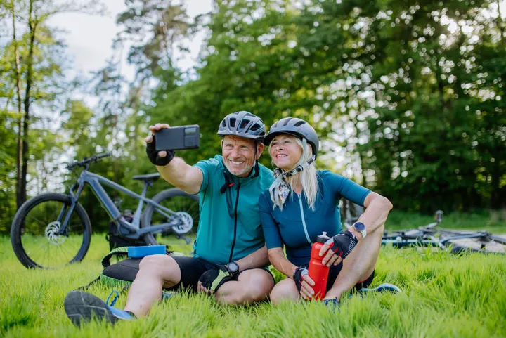 Zwei ältere Radfahrer machen ein gemeinsames Foto auf der Wiese